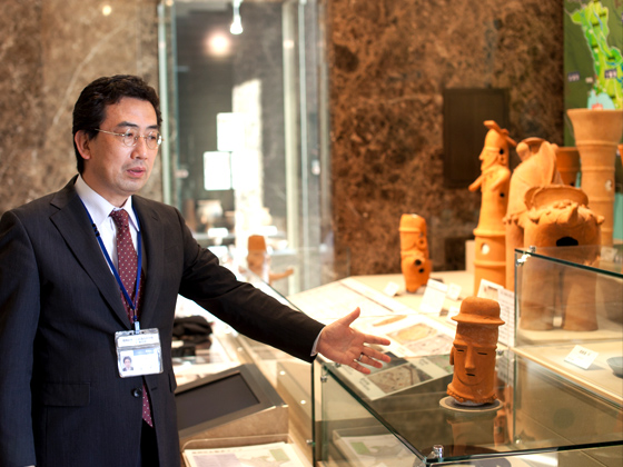 柴又八幡神社古墳で発見された帽子をかぶった埴輪は、渥美清さんの命日にあたる8月4日に出土。「寅さん埴輪」と呼ばれている。館内案内をしてくれたのは学芸員の谷口栄さん。