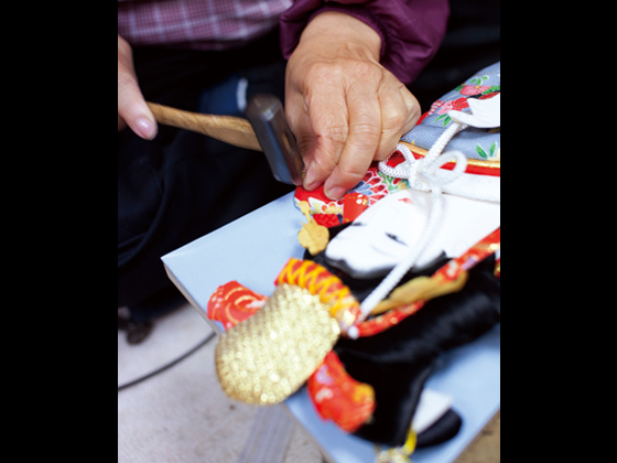 新田さんは人形の頭に「枕」と呼ばれる板を入れて釘で打ち込む。
