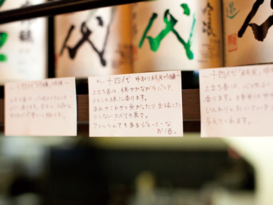 「日本酒って一番完成された酒だと思うんだよね。だからそのおいしさをもっと広めたい」。店内にはざっと320本の一升瓶が飾られ、その一つひとつに特徴や呑み方が書かれた田中さんのコメントがついている。壮観！